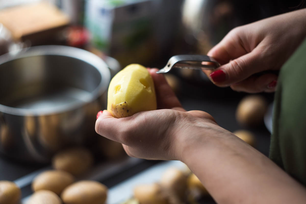 Person schält Kartoffeln mit einem ganz normalen Kartoffelschäler