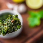 Foto traditioneller argentinischer Chimichurri Sauce vor einem Holzbrett-Hintergrund