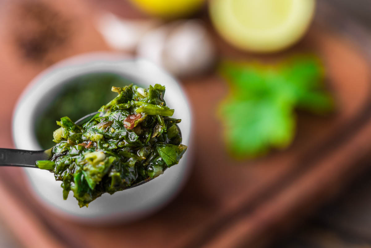 Foto traditioneller argentinischer Chimichurri Sauce vor einem Holzbrett-Hintergrund